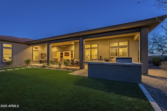 8768 E Granite Pass Rd, Scottsdale, AZ 85266 - rear view of house featuring an outdoor kitchen, a patio, stucco siding, and a lawn