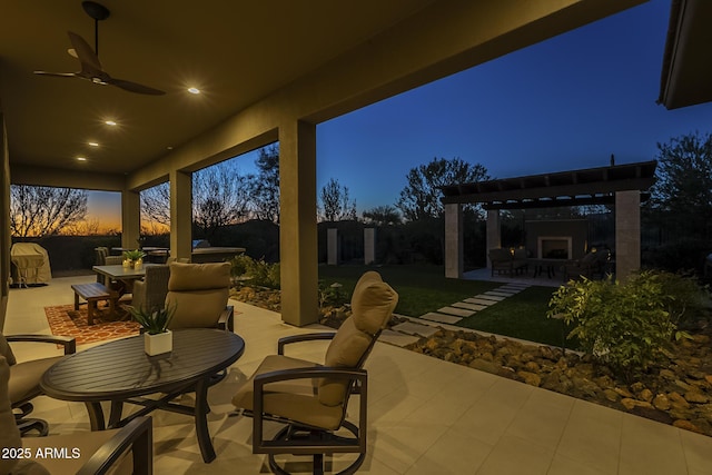 8768 E Granite Pass Rd, Scottsdale, AZ 85266 - patio terrace at dusk with outdoor dining space, ceiling fan, and exterior fireplace