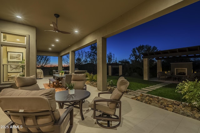 8768 E Granite Pass Rd, Scottsdale, AZ 85266 - patio at night with fence, outdoor dining space, an outdoor living space with a fireplace, and ceiling fan