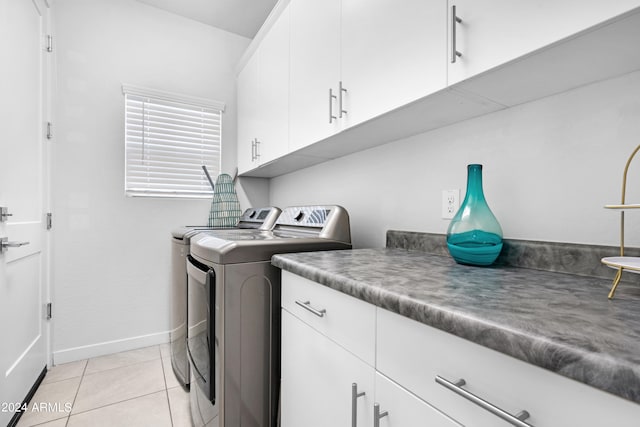 laundry area featuring washing machine and dryer, cabinets, and light tile patterned floors