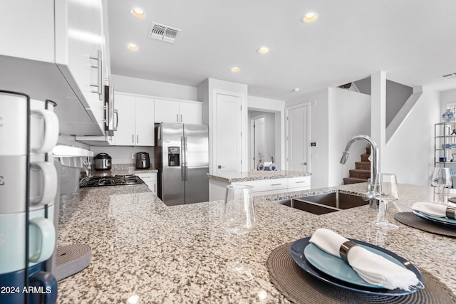 kitchen with light stone counters, sink, appliances with stainless steel finishes, and white cabinetry