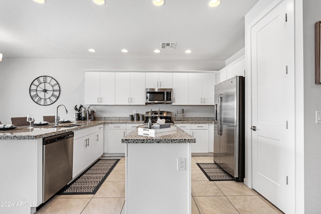 kitchen with stainless steel appliances, sink, kitchen peninsula, white cabinetry, and light tile patterned flooring