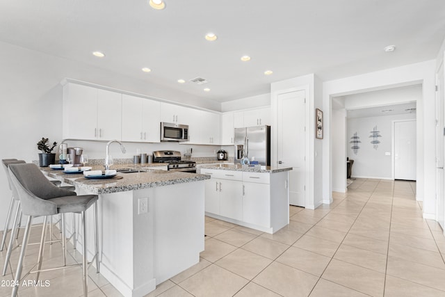 kitchen with appliances with stainless steel finishes, a center island, light stone countertops, and sink