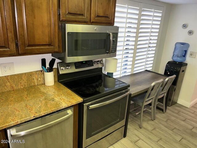 details with dark brown cabinets, stainless steel refrigerator, and light stone countertops