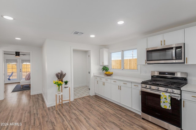 kitchen with light wood-type flooring, white cabinetry, appliances with stainless steel finishes, and french doors