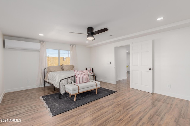 bedroom featuring ceiling fan, light hardwood / wood-style floors, and an AC wall unit