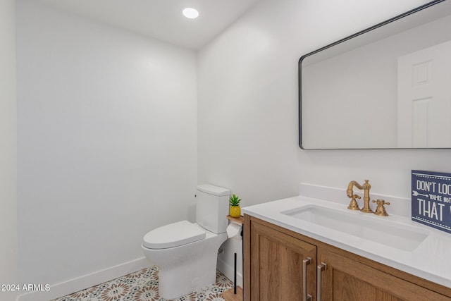 half bathroom with recessed lighting, vanity, toilet, and baseboards