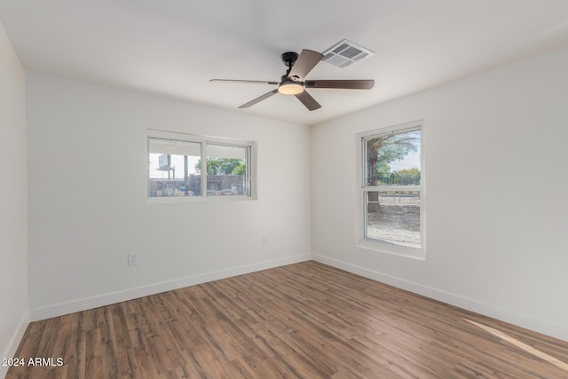 empty room featuring plenty of natural light, wood finished floors, visible vents, and baseboards