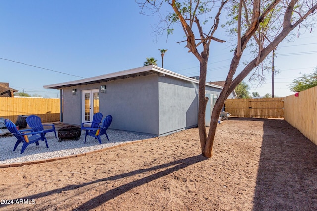 back of property with a fire pit and french doors