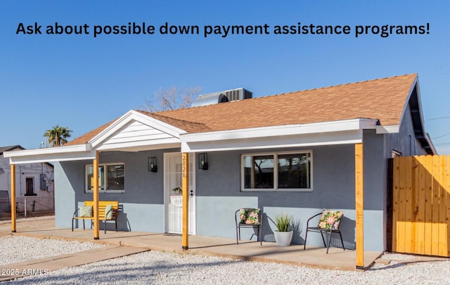 view of front of home with cooling unit, roof with shingles, fence, and stucco siding