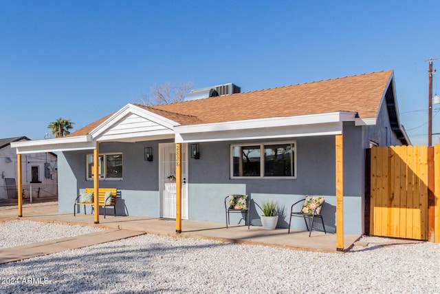 view of front of home featuring a shingled roof, central AC, fence, and stucco siding