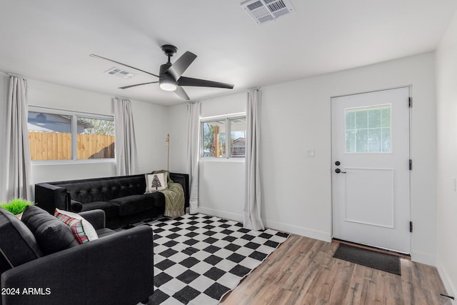 living area featuring ceiling fan, light floors, visible vents, and baseboards