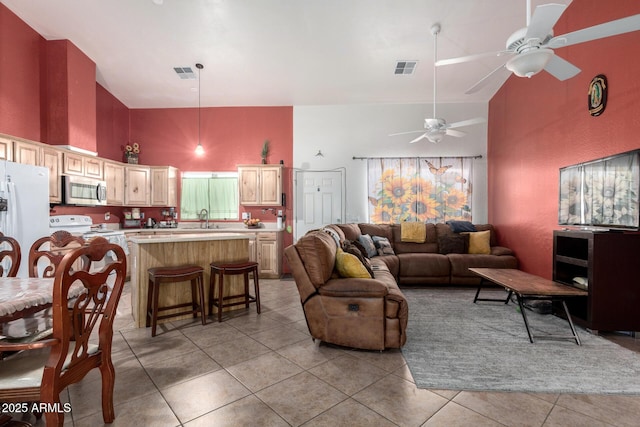 tiled living room featuring ceiling fan, sink, and high vaulted ceiling