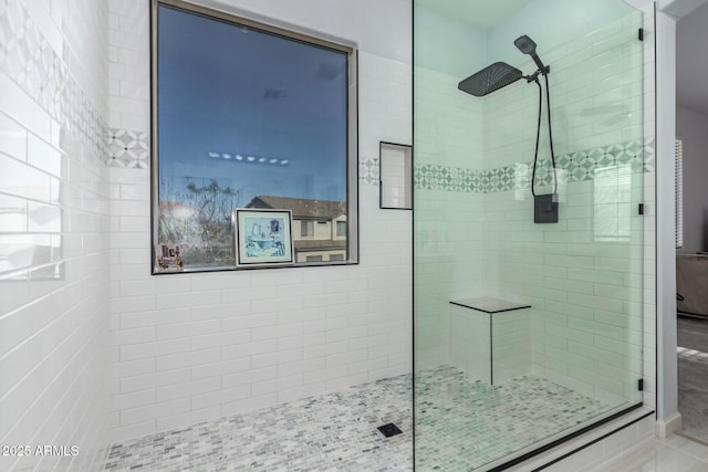 bathroom with a tile shower and tile patterned flooring