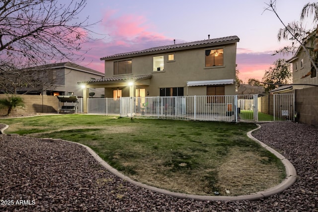 back house at dusk featuring a yard