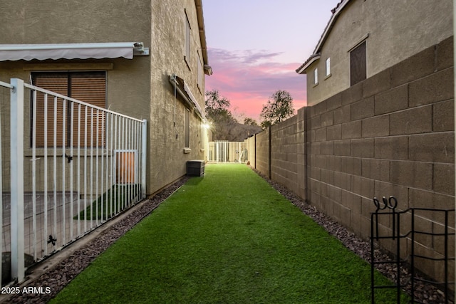 yard at dusk featuring central AC