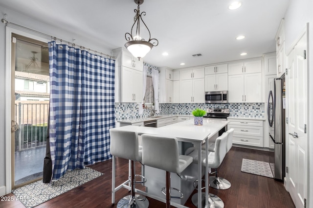 kitchen featuring pendant lighting, white cabinetry, appliances with stainless steel finishes, and tasteful backsplash