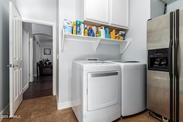 laundry area with cabinets, dark tile patterned flooring, and washing machine and clothes dryer