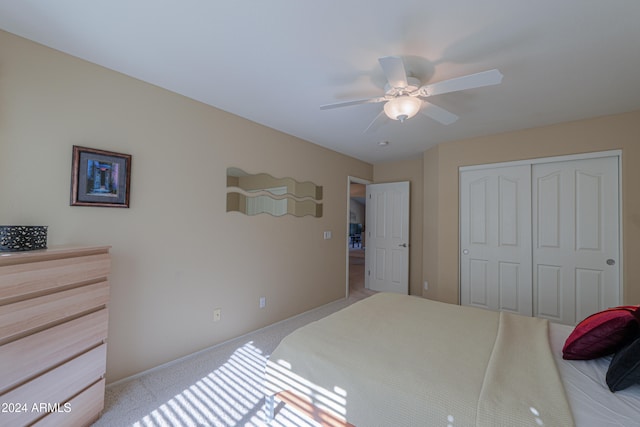 bedroom featuring ceiling fan, light carpet, and a closet