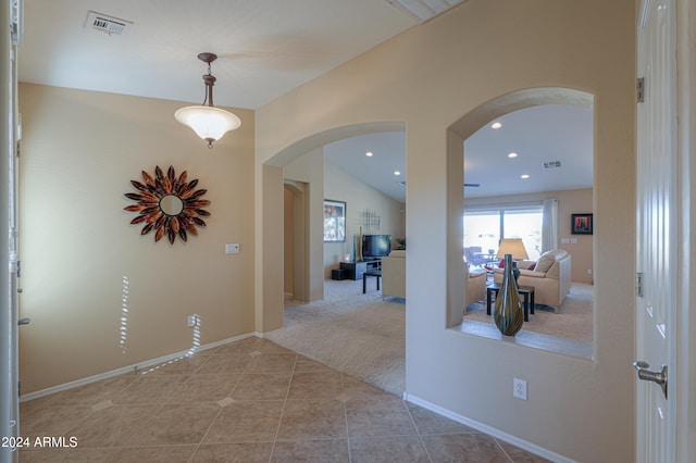 hallway with light carpet and vaulted ceiling