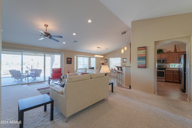 carpeted living room featuring ceiling fan with notable chandelier and vaulted ceiling