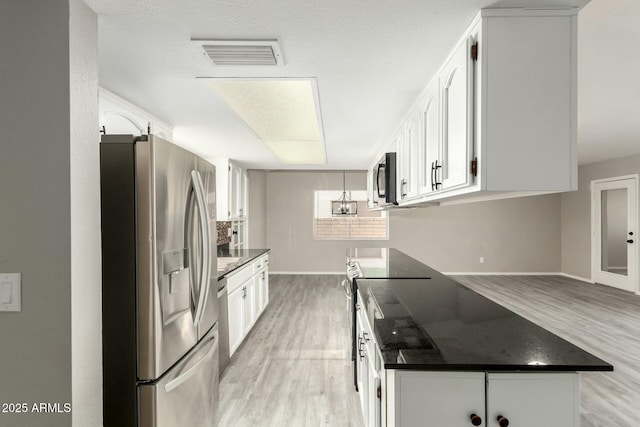 kitchen with white cabinetry, light hardwood / wood-style flooring, stainless steel appliances, and a textured ceiling