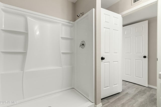 bathroom with hardwood / wood-style floors and a shower