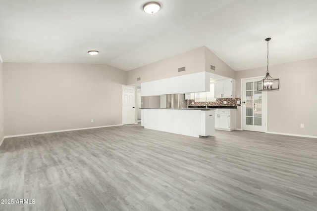 unfurnished living room featuring hardwood / wood-style flooring, vaulted ceiling, and a notable chandelier