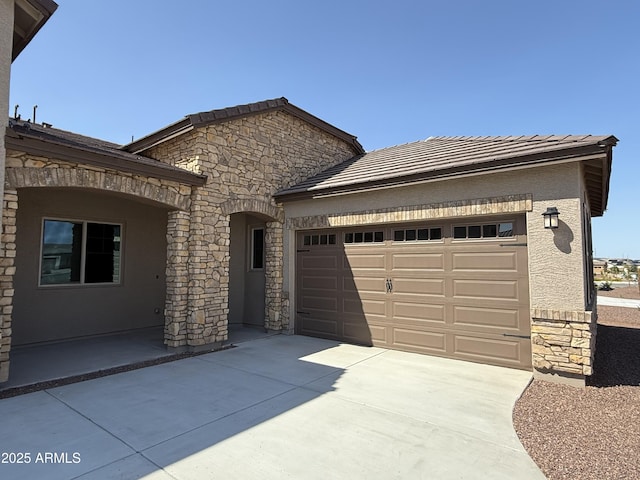 17308 W Royal Palm Rd, Waddell, AZ 85355 - view of front of property featuring stone siding, an attached garage, concrete driveway, and stucco siding