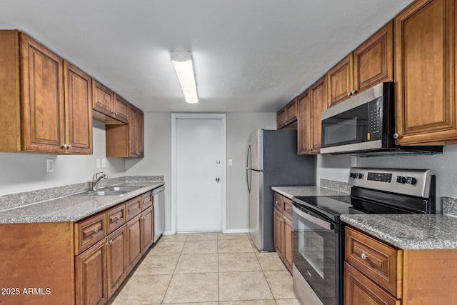 kitchen with a sink, appliances with stainless steel finishes, light tile patterned flooring, and brown cabinets