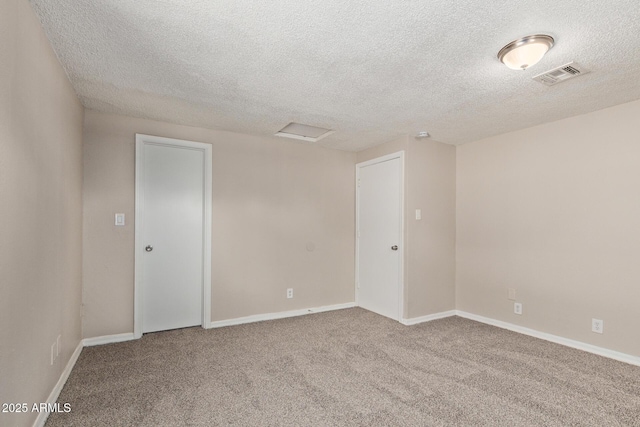 carpeted spare room with a textured ceiling, visible vents, and baseboards