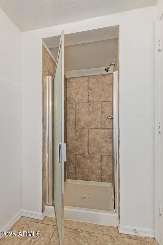 bathroom featuring baseboards, tile patterned flooring, and a shower stall