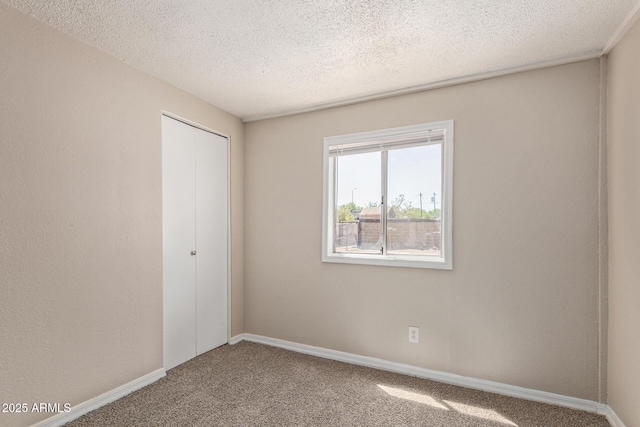 carpeted spare room featuring baseboards and a textured ceiling
