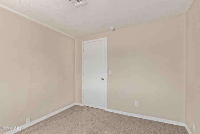 carpeted spare room with a textured ceiling, baseboards, and visible vents