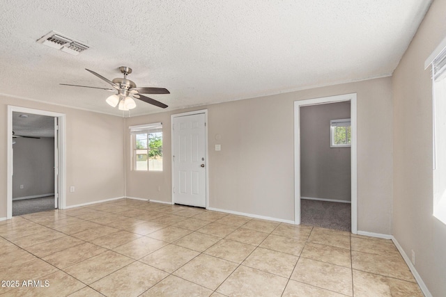 unfurnished room with a wealth of natural light, a textured ceiling, and visible vents