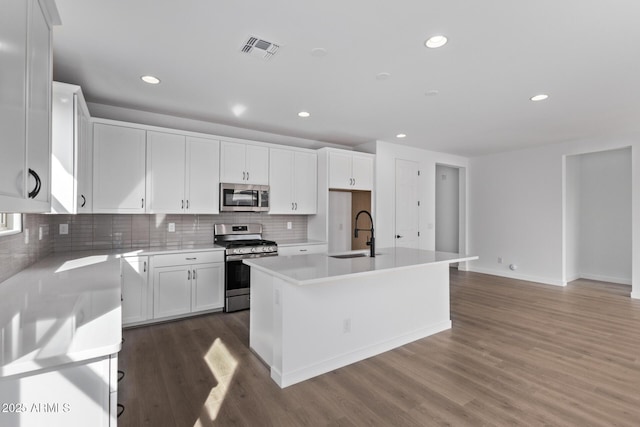 kitchen featuring sink, dark wood-type flooring, appliances with stainless steel finishes, a kitchen island with sink, and white cabinets