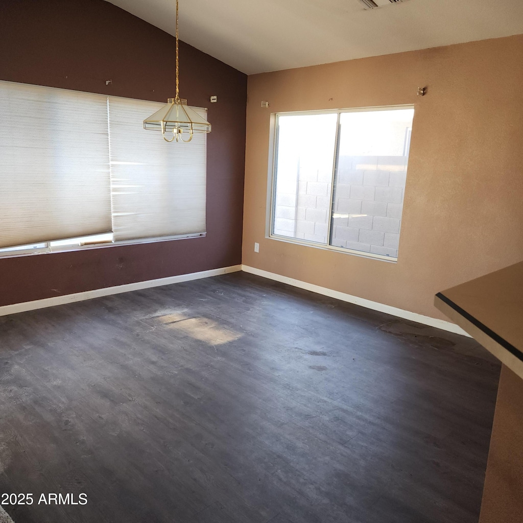 unfurnished dining area with vaulted ceiling, dark hardwood / wood-style flooring, and a chandelier