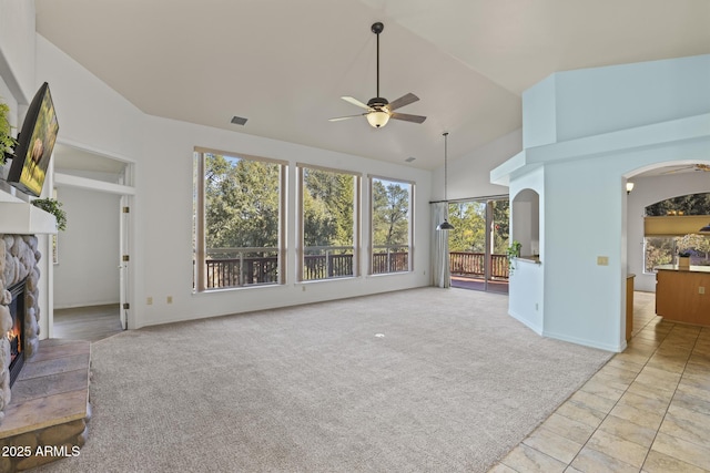 unfurnished living room featuring ceiling fan, light colored carpet, lofted ceiling, and a fireplace