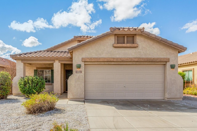 mediterranean / spanish house featuring a tiled roof, stucco siding, an attached garage, and concrete driveway