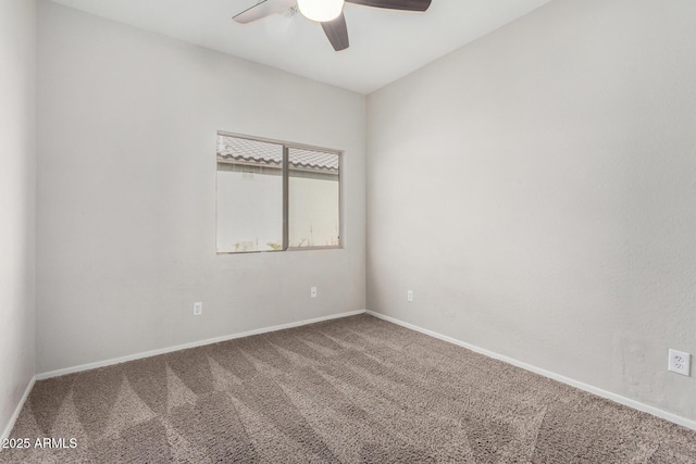 carpeted spare room featuring a ceiling fan and baseboards