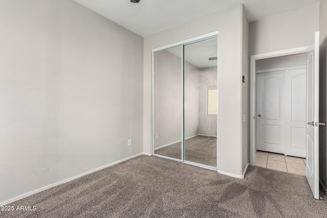 unfurnished bedroom with a closet, baseboards, and carpet flooring