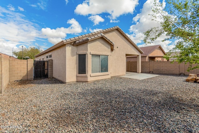 rear view of house featuring a patio, a gate, a fenced backyard, and stucco siding