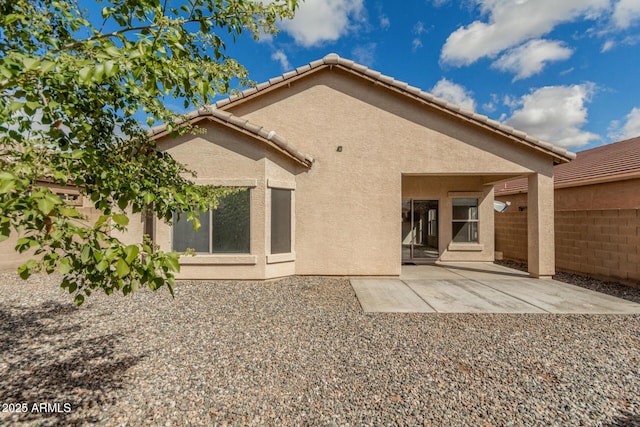 back of house with stucco siding, fence, a tile roof, and a patio area