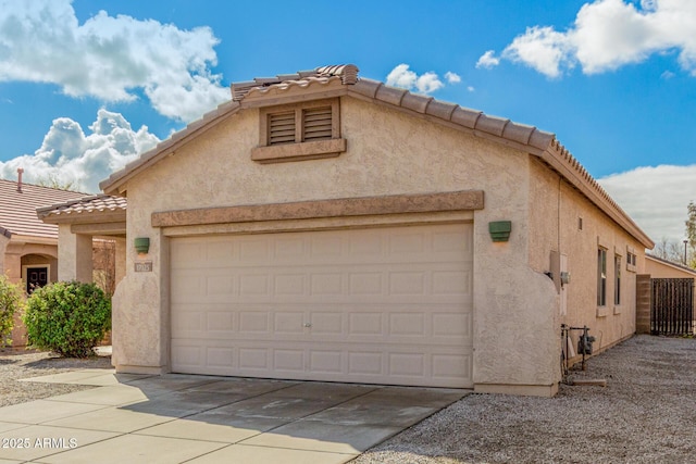 view of front facade featuring stucco siding, a tiled roof, and a garage