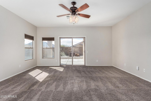 empty room with a wealth of natural light, dark colored carpet, baseboards, and a ceiling fan