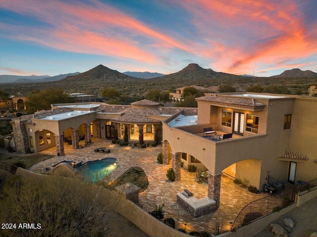 back house at dusk with a mountain view and a patio