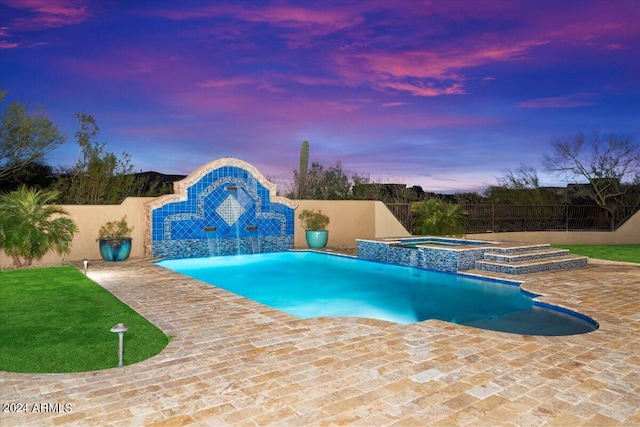 pool at dusk with an in ground hot tub, pool water feature, and a patio area