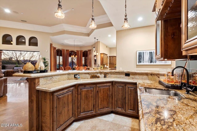 kitchen featuring sink, ornamental molding, light stone countertops, and hanging light fixtures