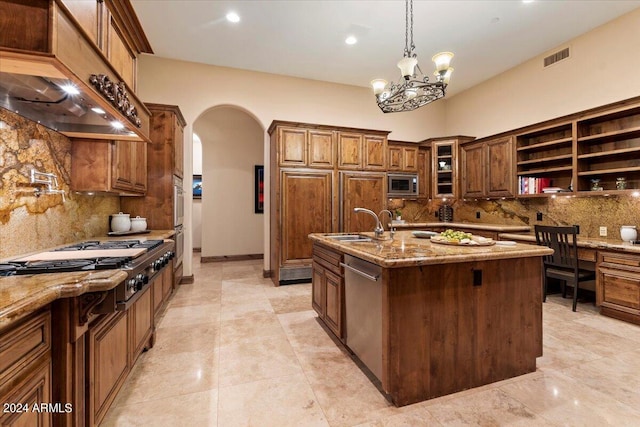 kitchen featuring sink, hanging light fixtures, a kitchen island with sink, light stone counters, and stainless steel appliances