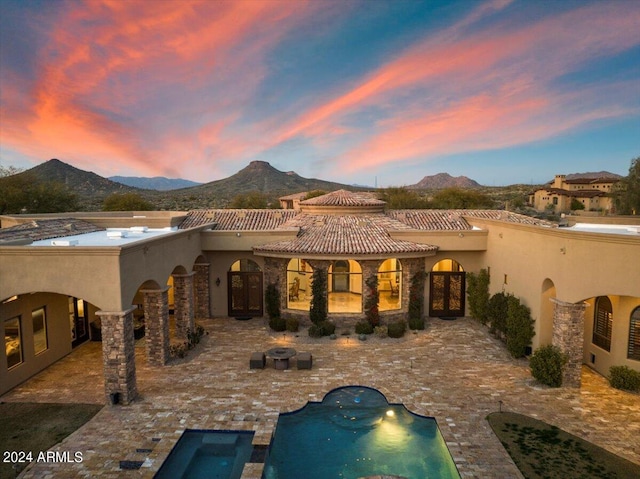 back house at dusk with a mountain view and a patio